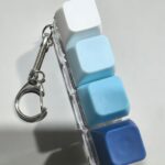 Blue and white 4-key keyboard fidget keychain close-up