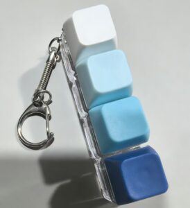 Blue and white 4-key keyboard fidget keychain close-up