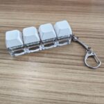 White 4-key keyboard clicker keychain on a desk