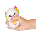 Hand squeezing a white and colorful axolotl squishy toy