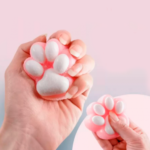 Hand squeezing a pink and white cat paw squishy toy