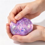 Hand squeezing purple glitter dumpling squishy toy