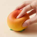 Hand pressing a peach-shaped squishy toy